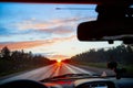 Red sunset view with shining sun from the car front window. Driving car during sunset concept. View on nature landscape and a road Royalty Free Stock Photo