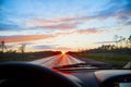 Red sunset view with shining sun from the car front window. Driving car during sunset concept. View on nature landscape and a road Royalty Free Stock Photo