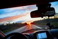 Red sunset view with shining sun from the car front window. Driving car during sunset concept. View on nature landscape and a road Royalty Free Stock Photo