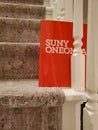 Red SUNY ONEONTA file folder standing on end between rungs on carpeted stairs Royalty Free Stock Photo