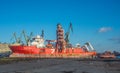 Red supply ship being reapired in a shipyard with scaffoldings