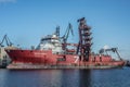 Red rusty supply ship being reapired in a shipyard with scaffoldings