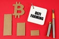 On a red surface lie the bitcoin symbol, a pen and a notepad with the inscription - DEFI farming