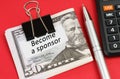 On a red surface lies a calculator, a pen, dollars and paper with the inscription - become a sponsor