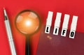 On the red surface there is a magnifying glass, a notepad and clothespins with the inscription - LIFO Royalty Free Stock Photo