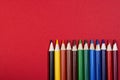 On the red surface there are wooden colored school pencils. Top view. Royalty Free Stock Photo
