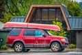 Red SUV with canoe tied to top driving through mountain town in the rain Royalty Free Stock Photo