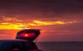 Red SUV car with sport design with open car truck parked on concrete road by the sea at sunset sky. Electric car technology Royalty Free Stock Photo