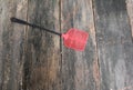 Red swatter fly, object made of plastic on Wood floor