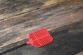 Red swatter fly, object made of plastic on Wood floor background