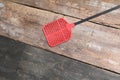 Red swatter fly, object made of plastic on Wood floor