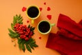 Red sweater, green and yellow mugs, hearts, rowan berries on orange background flat lay