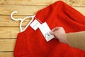 Red sweater on hangers on wooden background with Zara tag, winter sales