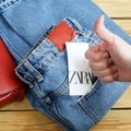 Red sweater and jeans on hangers on wooden background with Zara tag, winter sales