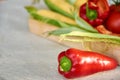 Red sweet bell pepper in the foreground on gray concrete surface close up. Fresh bell pepper and corn on blurred background Royalty Free Stock Photo