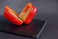 The red, sweet Bulgarian pepper is cut in half and lies on a black dish Royalty Free Stock Photo