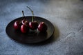 Red sweet cherries on a black plate on a dark surface Royalty Free Stock Photo