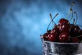 Red sweet cherries close up in a metal bucket on a dark and blue background. Summer taste. Royalty Free Stock Photo