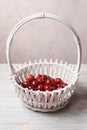 Red sweet cherries in a white basket on a white wooden table