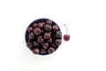 Red sweet cherry in a blue cup and one single berry on a white background Royalty Free Stock Photo