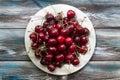 Red sweet cherry fruit in white plate on a gray-blue wooden surface Royalty Free Stock Photo