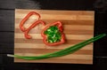 Red sweet pepper and green onion in water drops on wooden board. Sweet pepper half is filled with chopped green onions Royalty Free Stock Photo