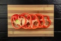 Red sweet pepper sliced into rings on a striped wooden board. Top view of round pieces of bell peppers with seeds and Royalty Free Stock Photo