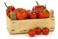 Red sweet peppers and tomatoes in a wooden crate