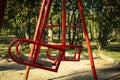 Red swings in city park in bright sunny morning Royalty Free Stock Photo