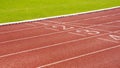 Red synthetic running tracks with numbers and green field in athletic outdoors stadium Royalty Free Stock Photo