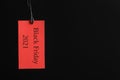 Red tag with words BLACK FRIDAY 2021 hanging on background. Space for text Royalty Free Stock Photo