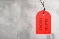 Red tag with words BLACK FRIDAY hanging on grey background. Space for text Royalty Free Stock Photo