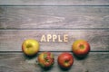 Red tasty apples fruits on a wooden table with apple word written on wood