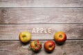 Red tasty apples fruits on a wooden table with apple word written on wood