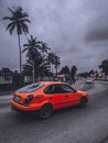 red taxi with black wheels driving under cloudy sky