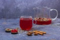 Red tea rooibos, hibiscus, karkade in glass cup and teapot among cinnamon, anise, cranberries on a dark background. Herbal, Royalty Free Stock Photo