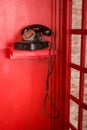 Red Telephone booth in English style. British phone box with black retro telephone standing in it. Royalty Free Stock Photo