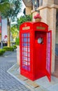 Red telephone booth with an open door on a summer sunny street Royalty Free Stock Photo