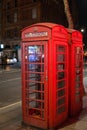 Red Telephone Box in the night in London with light reflections.