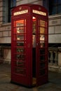 Red telephone box in yellow light at night with door ajar Royalty Free Stock Photo