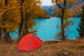 Red tent near beautiful mountains lake with turquoise water and colorful forest around. Tourism, trekking in autumn season concept Royalty Free Stock Photo