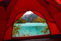 Red tent near beautiful mountains lake with turquoise water and colorful forest around. Tourism, trekking in autumn season concept Royalty Free Stock Photo