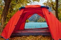 Red tent near beautiful mountains lake with turquoise water and colorful forest around. Tourism, trekking in autumn season concept Royalty Free Stock Photo