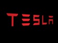 Red Tesla logo on a Black background