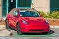 Red Tesla Model 3 vehicle plugged-in and charging at ChargePoint charging station