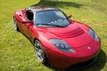 Red Tesla Roadster Sports Car Front Side in Green Field Royalty Free Stock Photo