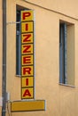 red text of the sign with the text pizzeria which in Italian is the place where pizzas are served