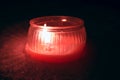 Red textured candle with flame in the snow during darkness