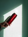 Red thermos can bottle in male hands against wall with harsh shadow. Hot tea coffee drinking in cold autumn winter weather Royalty Free Stock Photo