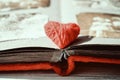 Red thread heart on open photo album on wooden table background. Vintage book or photo album with thread heart Royalty Free Stock Photo